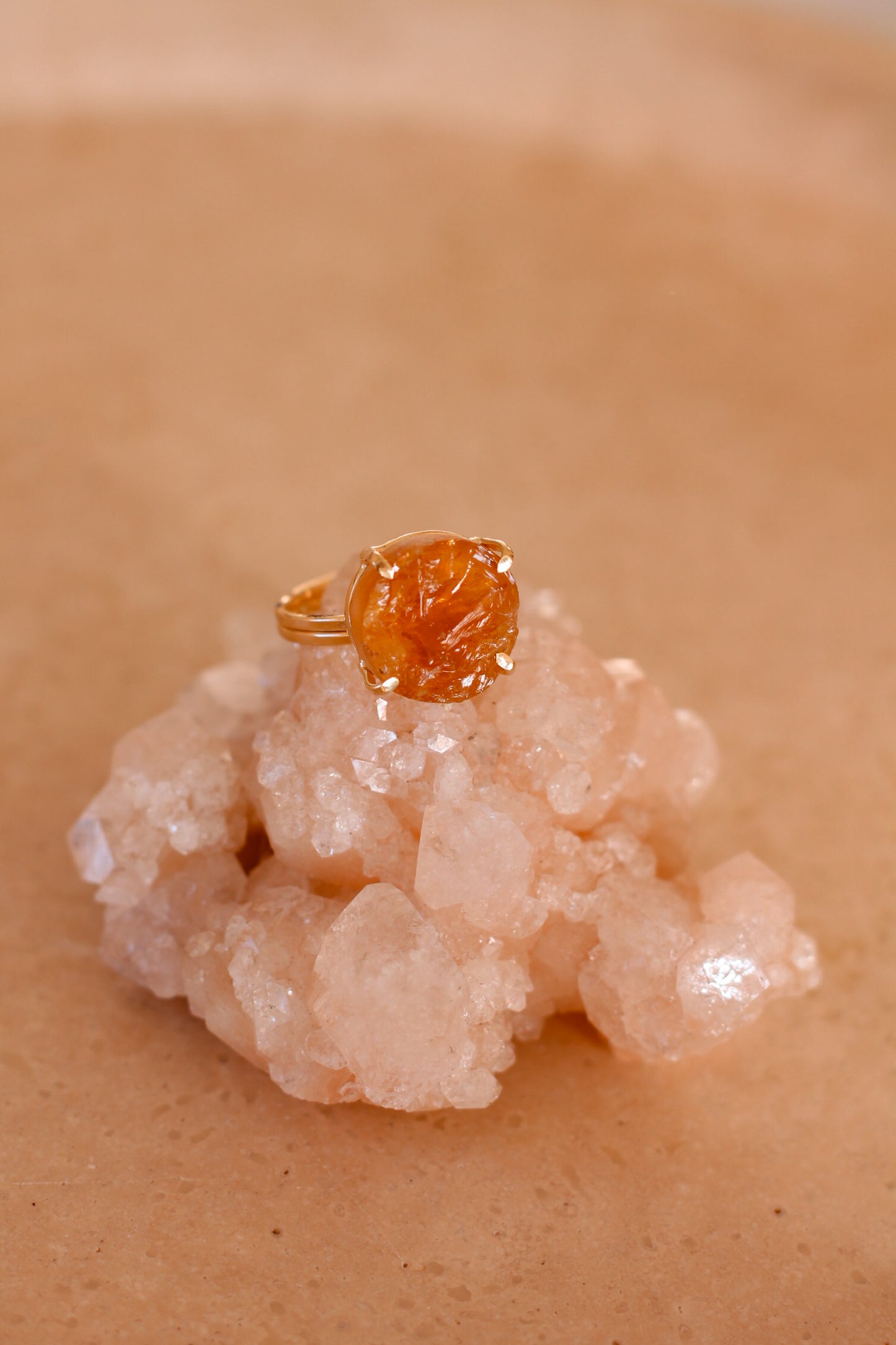 Gouden ring met een Citrien round edelsteen, gepresenteerd op een witte kristal.