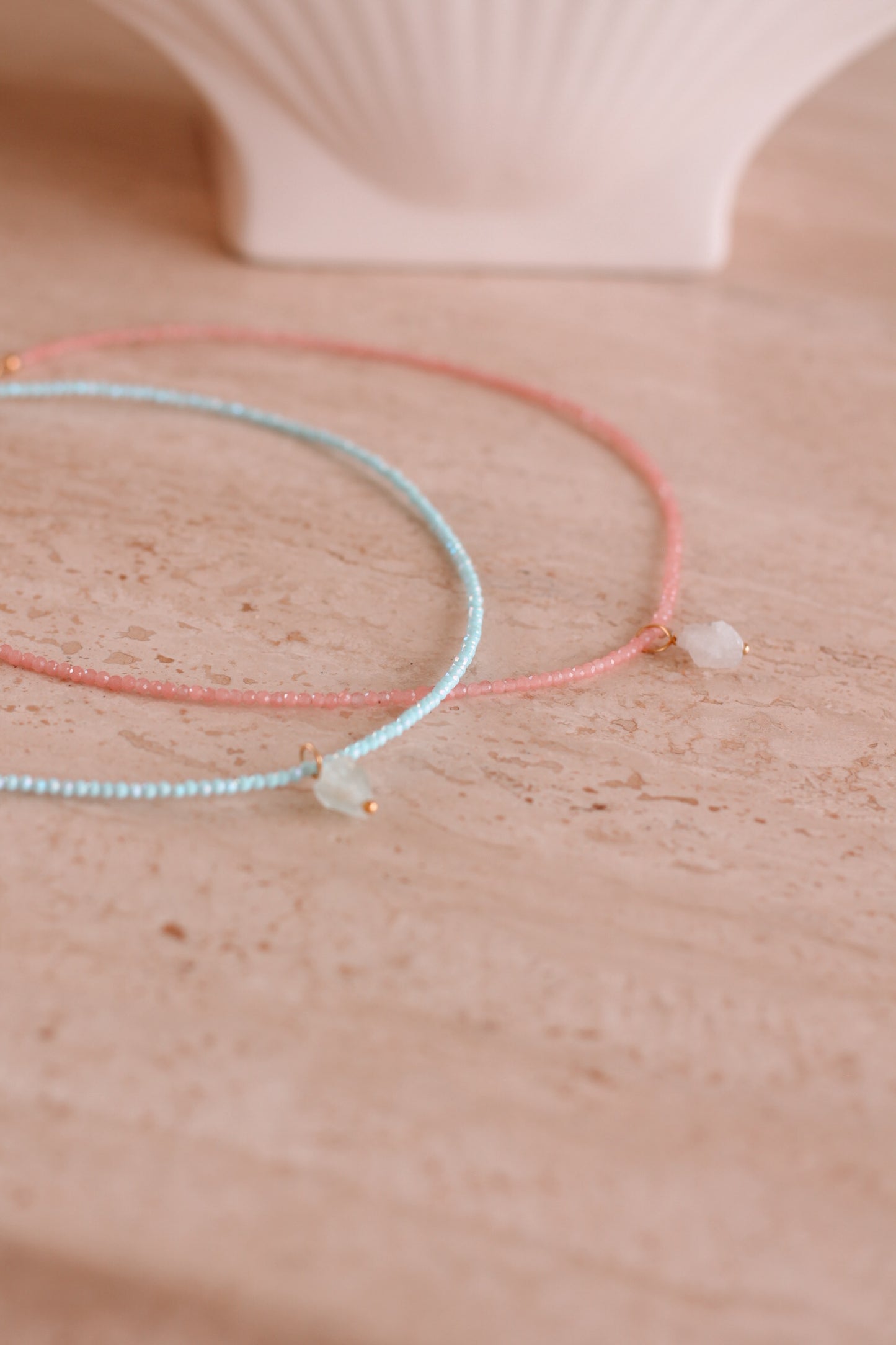 Detail shot van de kristal kettingen roze en blauw