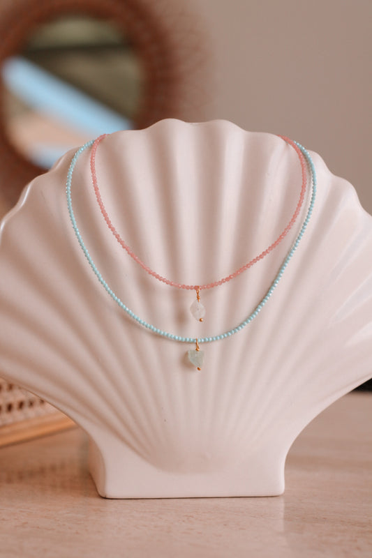 2 kristal kettingen rond een schelp. 1 roze en 1 blauwe.
