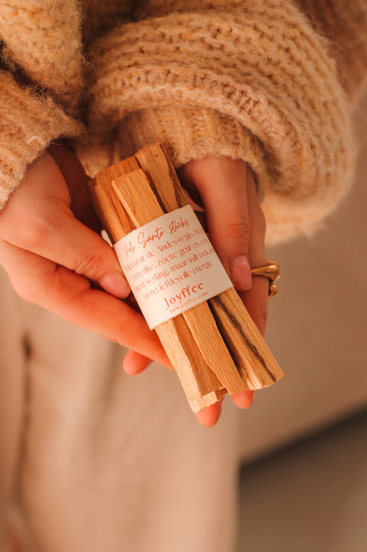 Een persoon houdt een set van 5 Palo Santo sticks vast.