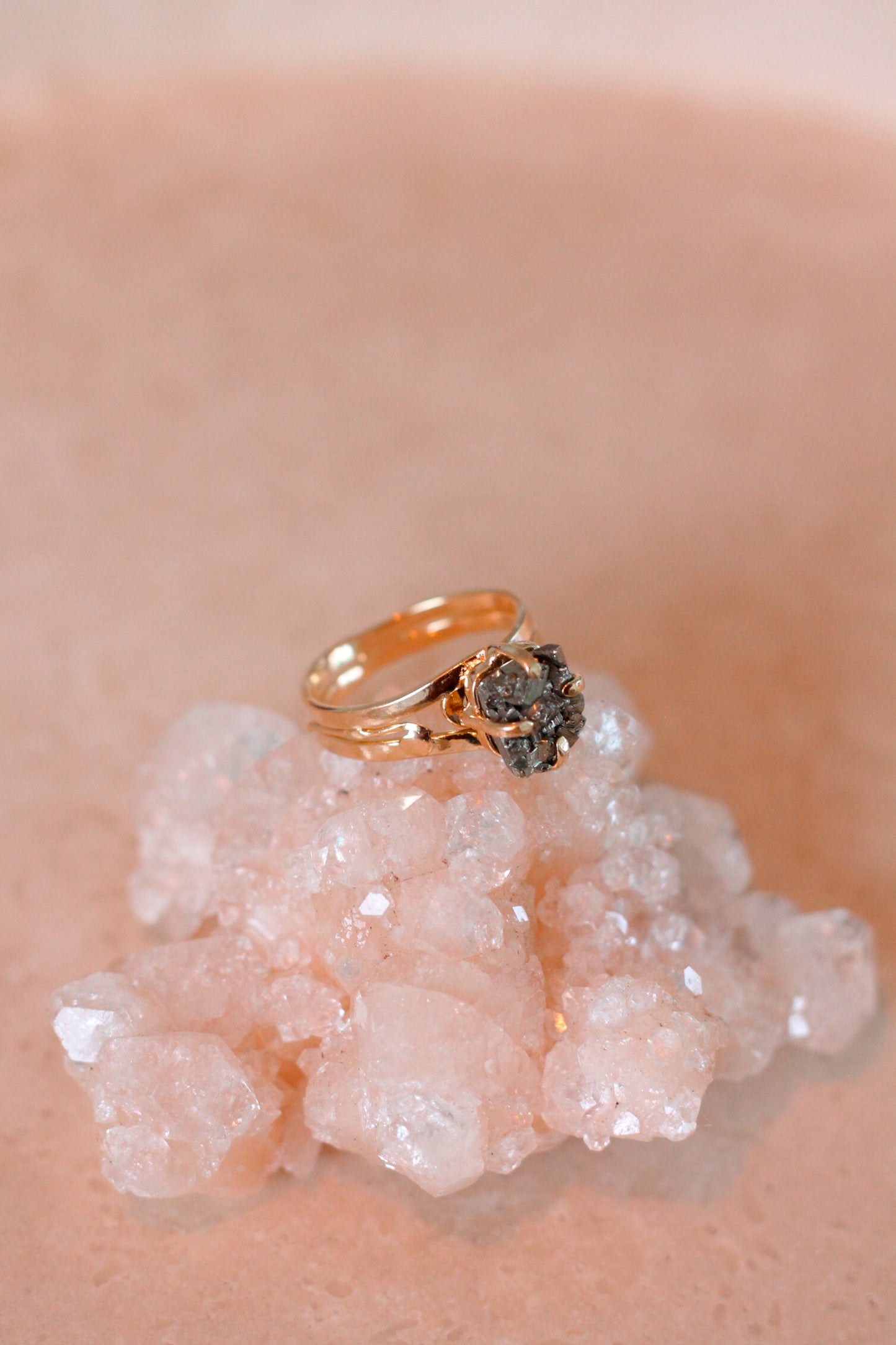 Gouden ring met een Pyriet edelsteen, gepresenteerd op een witte kristal.