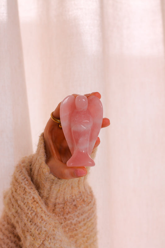 Een hand houdt de grote variant van de Rozenkwarts Beschermengel vast.