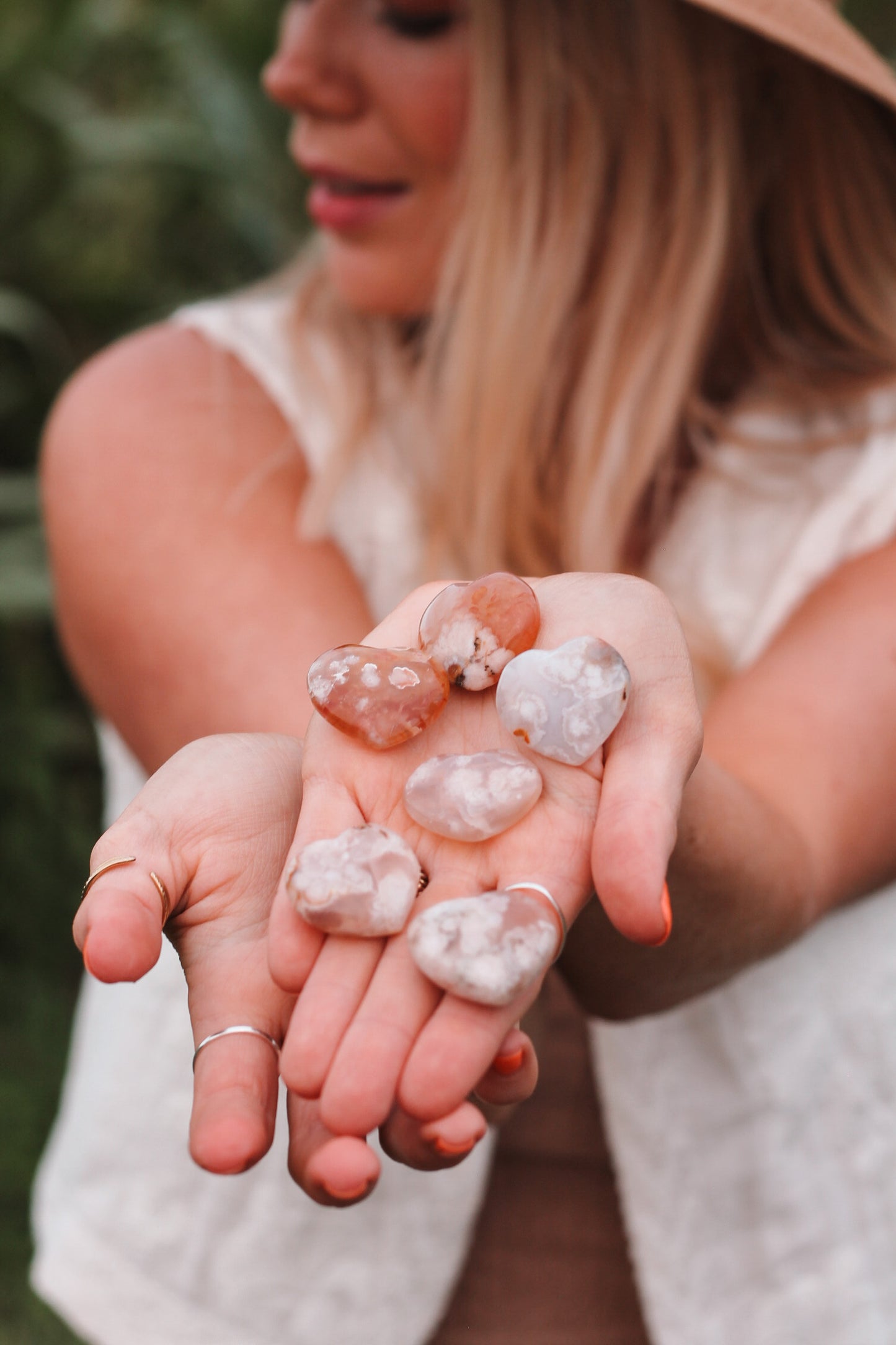 Verschillende soorten Flower Agaat hartjes, in de handen van Joyce Lemmens die je wazig in de achtergrond ziet.