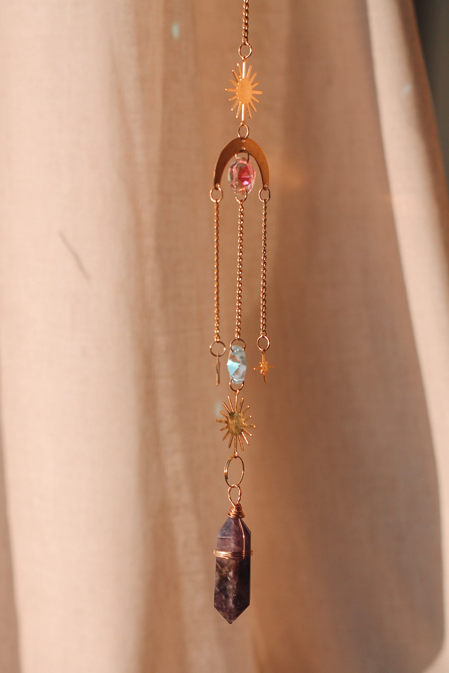 Suncatcher met feng shui kristallen en een kristal punt, bestaande uit een metalen zon en maan, met daaraan hangend verschillende kristallen en sterren