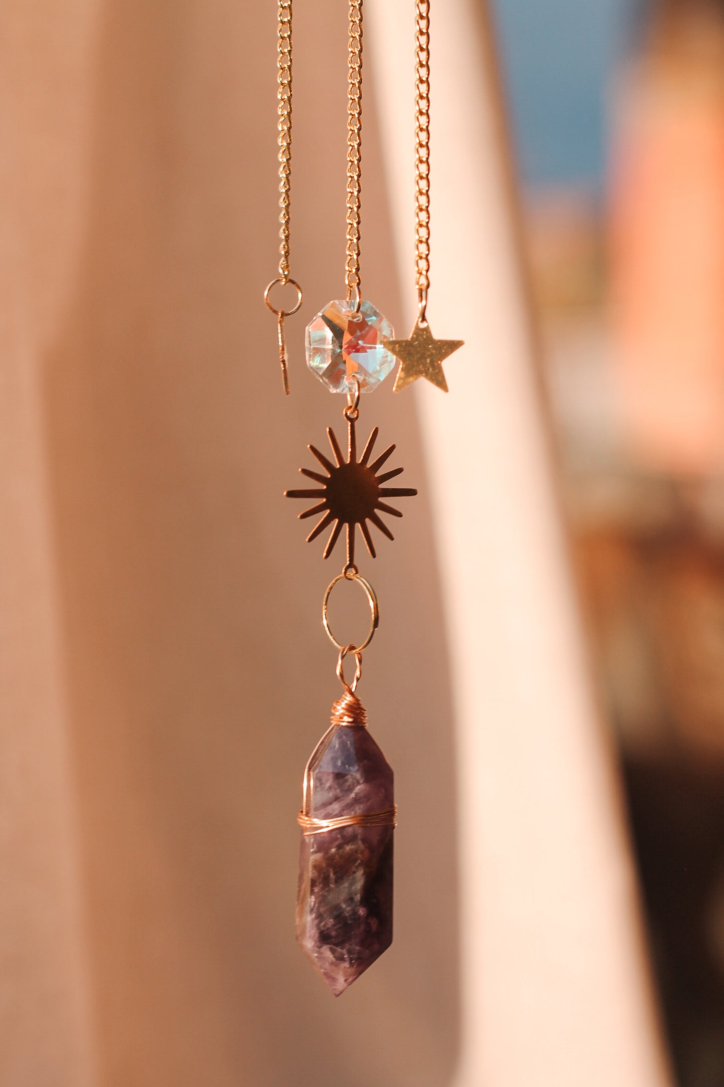Suncatcher met feng shui kristallen en een kristal punt, bestaande uit een metalen zon en ster, met daaraan hangend verschillende kristallen en sterren