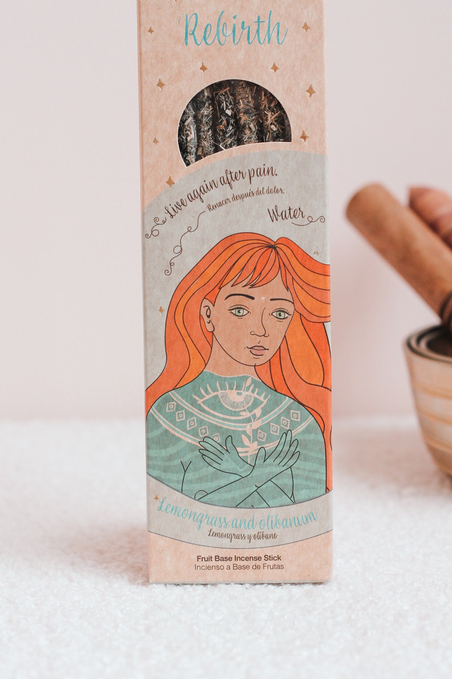 Een verpakking van wierookstokjes gemaakt van bruin karton met een venster waardoor de wierookstokjes zichtbaar zijn. Op de voorkant is een illustratie van een persoon te zien. Element water.