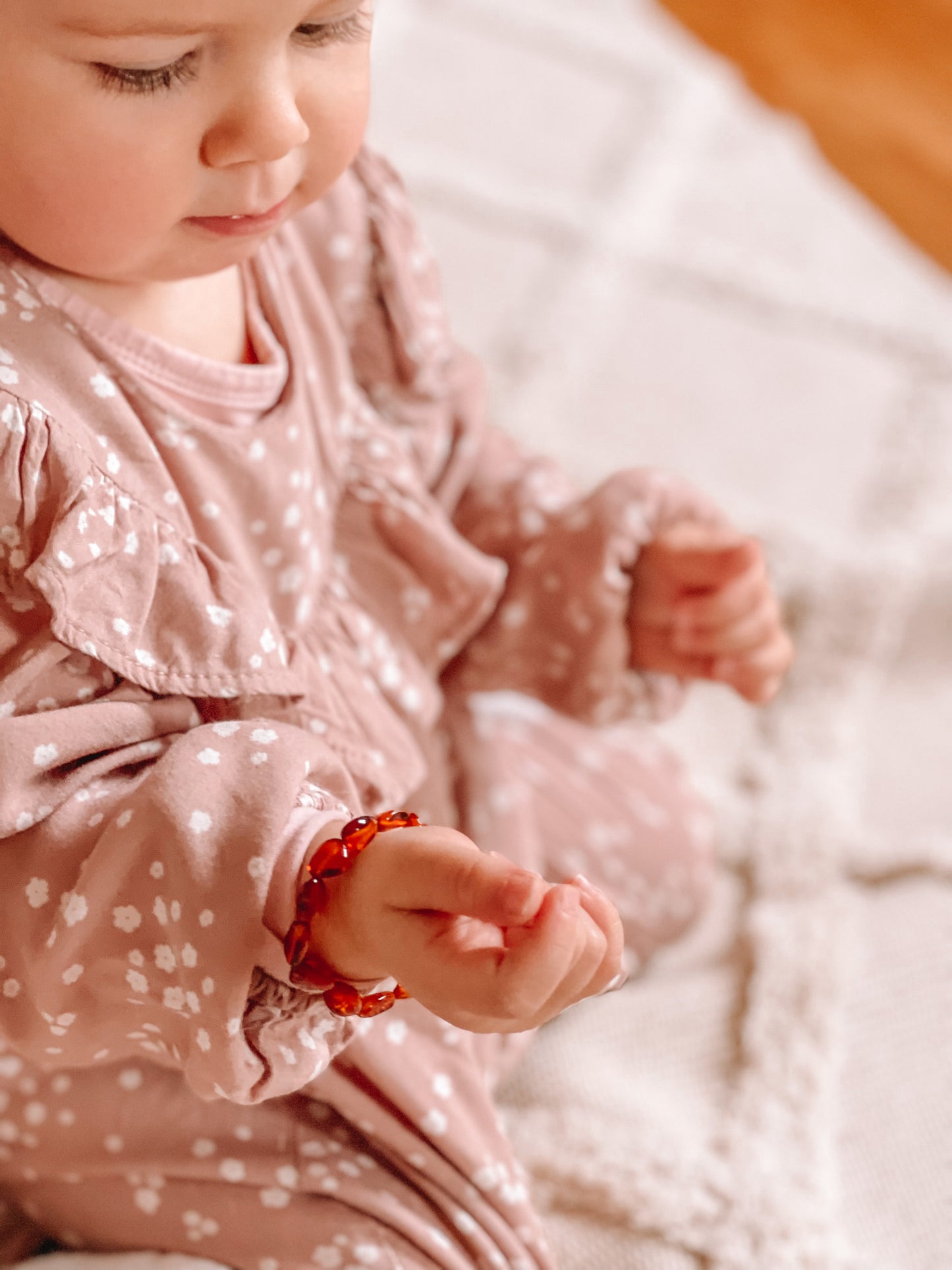 Afbeelding van een baby met rond de pols een Barnsteen armbandje.