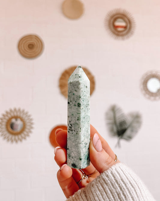 Een hand houdt een puntige, Mariposiet kristal vast.