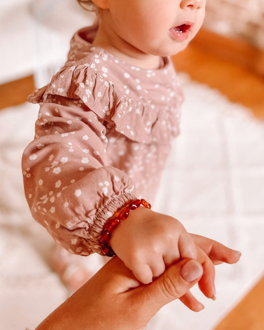 Afbeelding van een baby met rond de pols een Barnsteen armbandje.