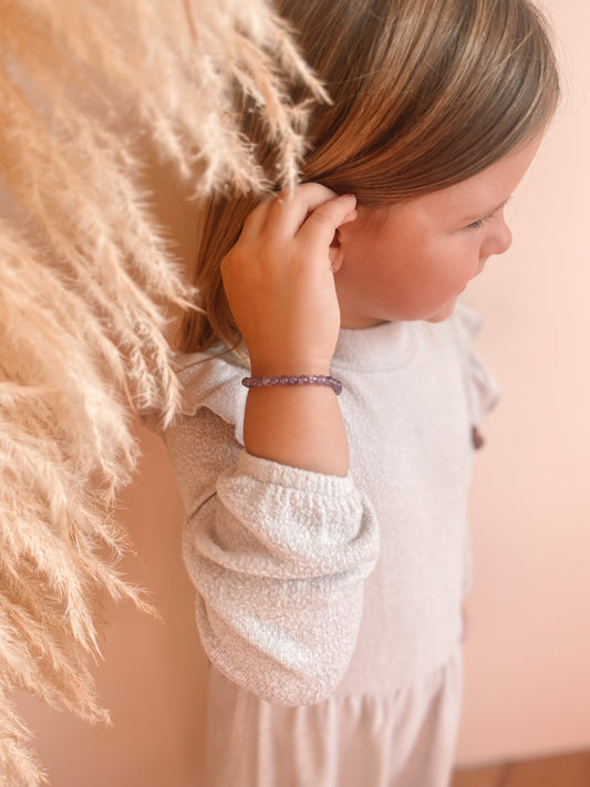 Kindje dat een edelsteen armbandje draagt rond haar pols. 